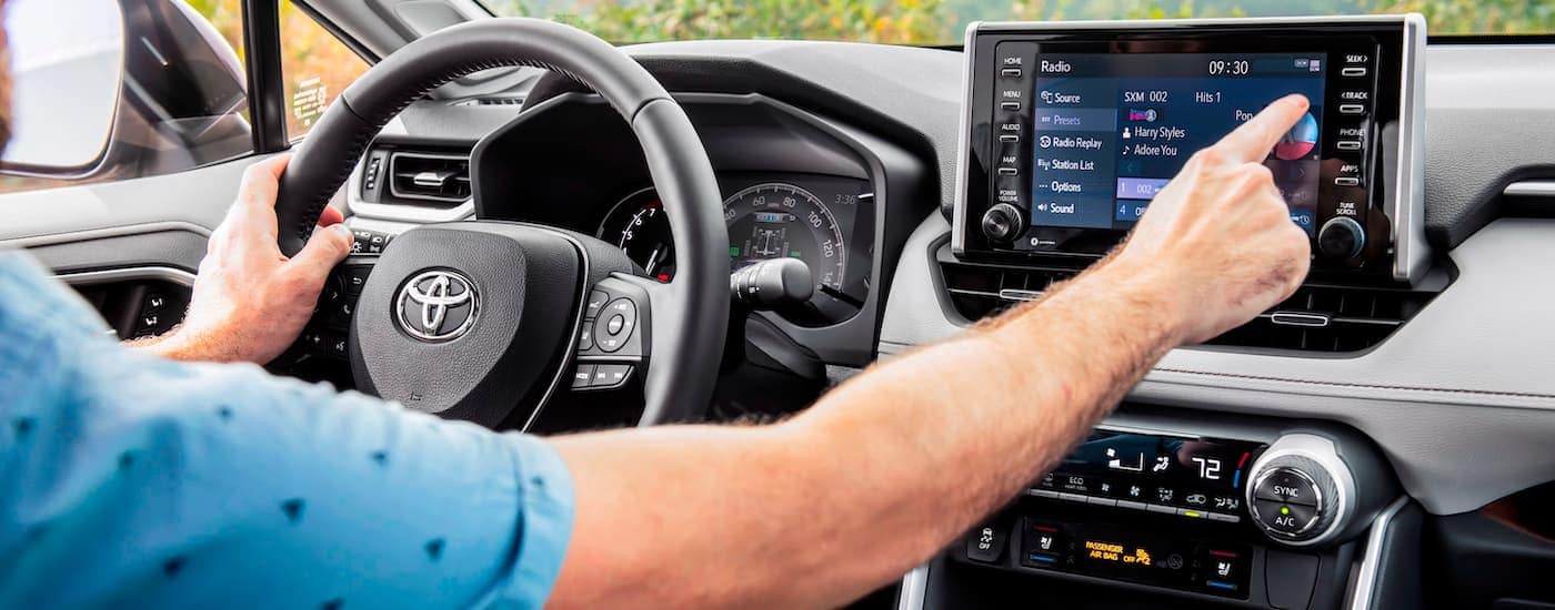 image of a person driving a Toyota and tapping something on the touchscreen console